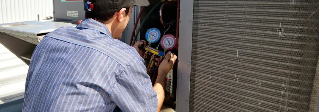 HVAC technician servicing a condenser unit in Eldridge
