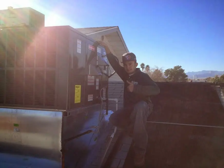 HVAC technician performing AC Tune-Up on a rooftop unit in Eldridge